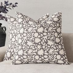 a black and white pillow sitting on top of a couch next to a vase filled with flowers