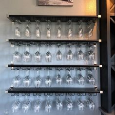 the wine glasses are lined up on the wall in front of the painting above them