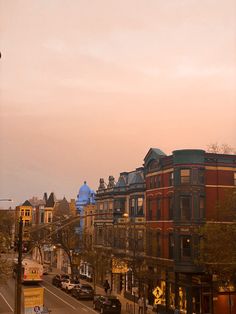 a city street filled with lots of traffic under a pink sky at sunset or dawn