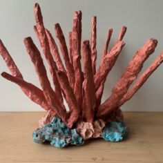 a coral sculpture sitting on top of a wooden table next to a blue and pink rock