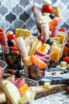 several cups filled with different types of fruit and crackers on top of a cutting board