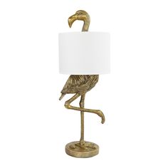 a gold flamingo lamp with a white shade on it's head and legs