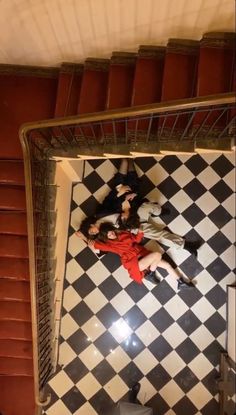 two people laying on the ground in front of a black and white checkered floor