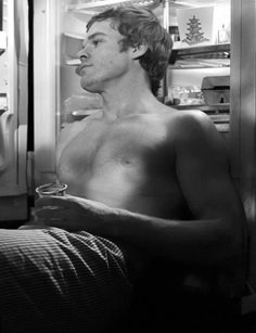 a shirtless man sitting in front of an open refrigerator