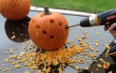 two pumpkins are being carved on top of a car with an electric driller