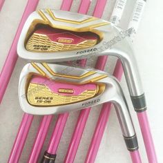 pink and gold golf clubs are lined up next to each other on the table with pencils