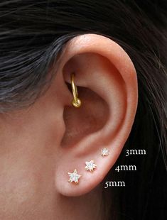 a woman's ear with three small stars on the top and one behind her ear