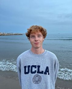 a young man standing on the beach in front of the ocean