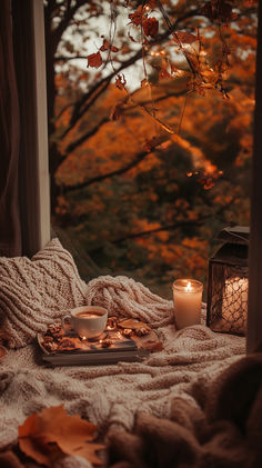 a candle and some leaves on a bed with a window in the backround