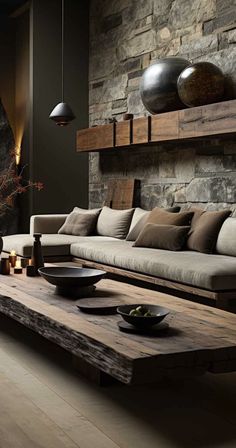 a living room filled with lots of furniture and stone wall behind the couches is a wooden coffee table