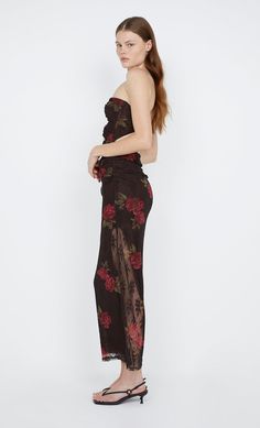 a woman in a strapless top and floral print pants is posing for the camera