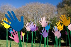 several colorful hand prints are placed in the grass next to each other on green sticks