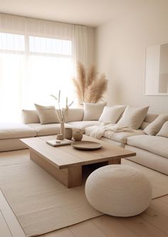 a living room with white couches and pillows on top of the floor next to a large window