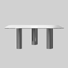 a white table with three metal legs on it's sides and a gray background