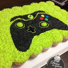 a cupcake decorated with green frosting and a video game controller on it's side