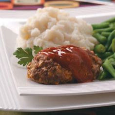 meatloaf with gravy, mashed potatoes and green beans on a white plate