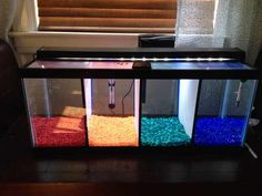 a fish tank filled with different colored rocks and gravel in front of a window sill