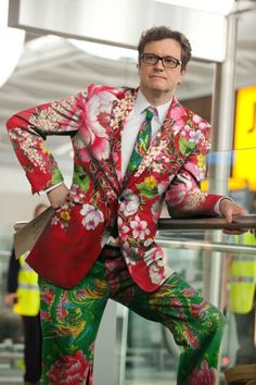 a man in a colorful suit and tie posing for the camera with his hands on his hips