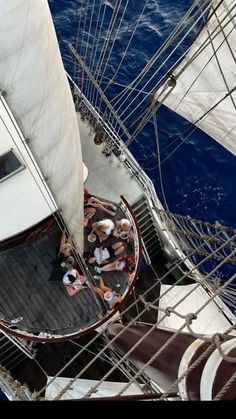 several people are sitting on the deck of a sailboat