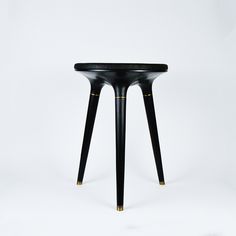 a small black table with gold legs on a white background