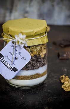 a jar filled with different types of food on top of a wooden table next to nuts