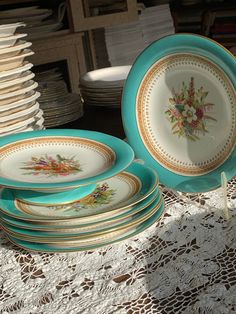 a table topped with lots of plates on top of a white doily covered table