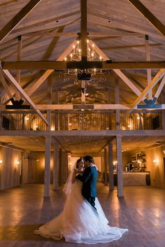 a bride and groom standing in the middle of a large room with chandeliers