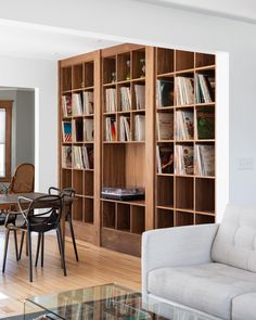 a living room filled with furniture and bookshelves next to a dining room table