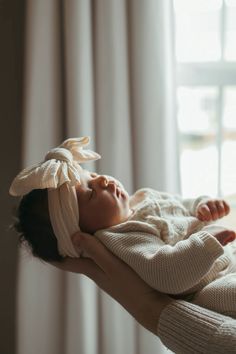 a woman holding a baby in her arms with a bow on it's head