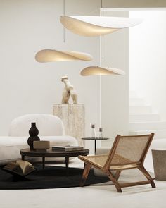 a living room filled with white furniture and lots of lights hanging from the ceiling above