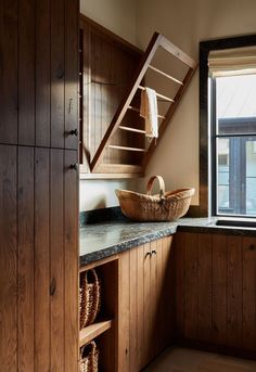 a kitchen with wooden cabinets and a basket on the counter next to an open window