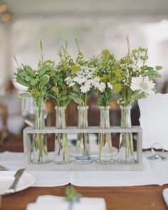 four vases filled with flowers sitting on top of a table next to plates and utensils