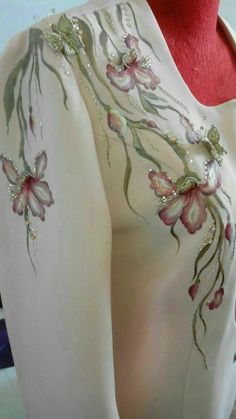 a woman's white top with pink flowers on it and beaded trimmings