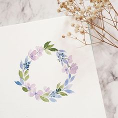 a card with watercolor flowers on it next to a dried plant and some twigs