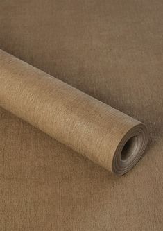 a roll of tan colored fabric on top of a tablecloth with a brown background