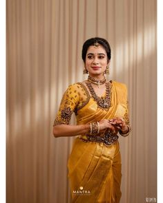 a woman in a yellow sari is holding her hands together and posing for the camera