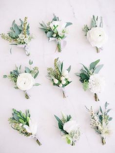 a bunch of flowers that are sitting on a white tablecloth with greenery around them