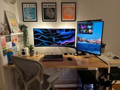 a desk with two computer monitors and a keyboard on it, in front of some pictures