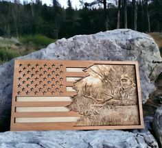 an american flag is on top of a rock next to a plaque with the image of a soldier