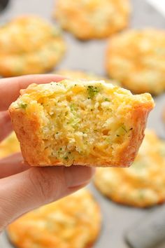 a person holding up a muffin in front of some other muffins