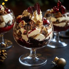 three desserts in glass bowls on a table with christmas decorations and lights behind them