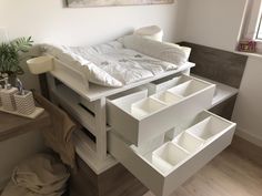 a white bed with drawers underneath it in a room