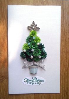 a card with a christmas tree made out of green and white flowers on it's side