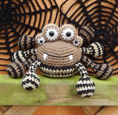 a crocheted spider sitting on top of a wooden shelf