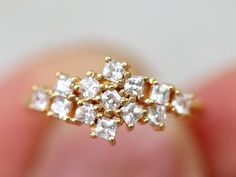 a close up of a person's hand holding a gold ring with white stones