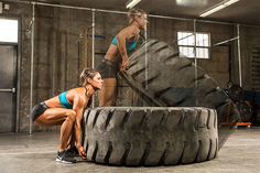 two women doing push ups on large tires