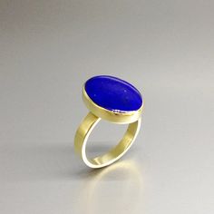 Oval classic Lapis Lazuli ring with 18k gold. Unique gift for her, girlfriend, wife, September and December birthstone, anniversary gift. This ring is a timeless classic and lets the stone speak with all its natural beauty. This beautiful ring is worked with the technique of inlay, which means the stone is worked seamlessly into the 18K gold.All our stones are natural stones and our jewelry is handmade, slight differences in color and size may occur. Our inlay work is made with real stone and NO Elegant Gold Rings With Tanzanite, Elegant Gold Tanzanite Rings, Oval Cabochon Jewelry With Smooth Bezel For Gift, Elegant Blue Jewelry With Smooth Bezel, Elegant Blue Birthstone Ring With Bezel Setting, Modern Jewelry With Smooth Bezel For Gift, Oval Jewelry With Smooth Bezel For Wedding, Blue Birthstone Ring With Bezel Setting For Formal Occasions, Formal Solitaire Jewelry With Oval Cabochon