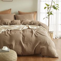 a bed with brown linens and pillows in a room next to a potted plant