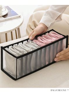 a person is holding an organized drawer with pink and white items in it on a table