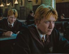 two men sitting at desks in harry potter's school with one man looking off to the side